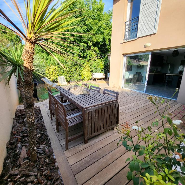 une terrasse en bois avec une table, des chaises et un palmier dans l'établissement Villa Isalia, proche Aix-en-Provence, à Rousset