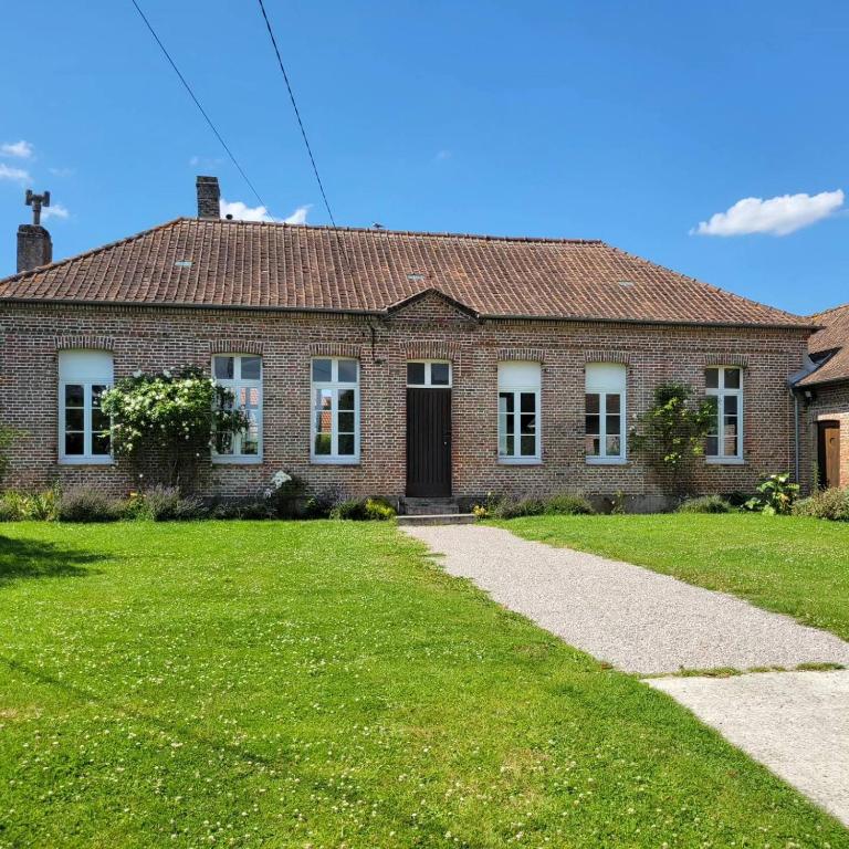 une maison en briques avec une pelouse verte devant dans l'établissement Le Presbytère de la côte d'opale, à Nempont-Saint-Firmin