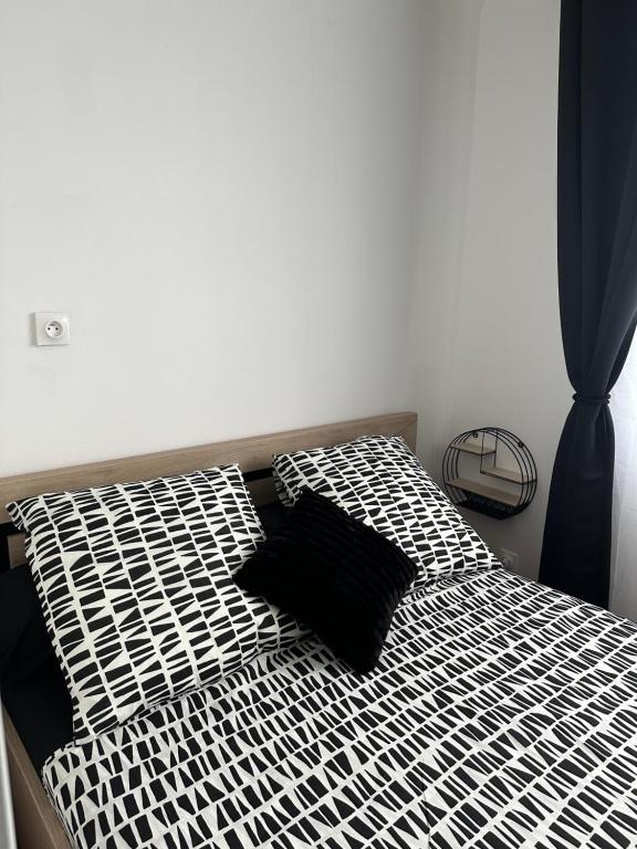 - un lit avec des draps et des oreillers en noir et blanc dans l'établissement Sweet Home !, à Athis-Mons