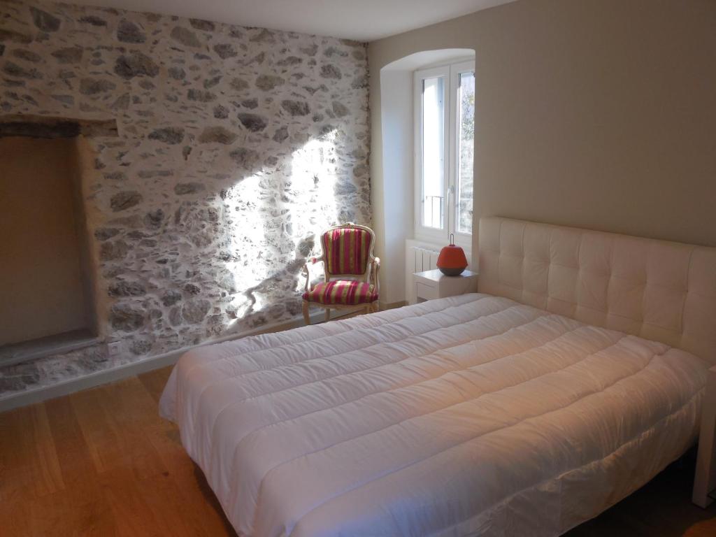 - une chambre avec un lit dans une pièce dotée d'un mur en pierre dans l'établissement Saint Christophe, à Omessa