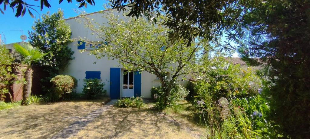 une maison blanche avec une porte bleue et des arbres dans l'établissement Maison familiale pour 10 personnes au centre à St Georges d'Oleron, à Saint-Georges-dʼOléron