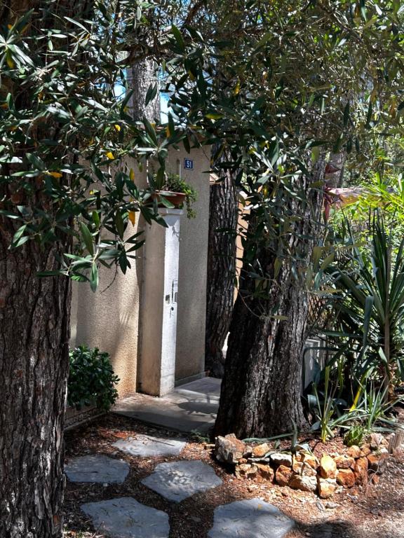 un bâtiment avec un arbre et une passerelle entre deux arbres dans l'établissement Cabanon à Sanary sur mer au coeur de Portissol., à Sanary-sur-Mer