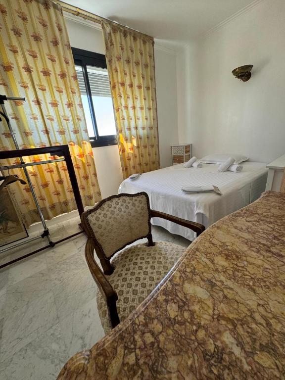 a bedroom with two beds and a chair and a window at Lilas house in Les Lilas