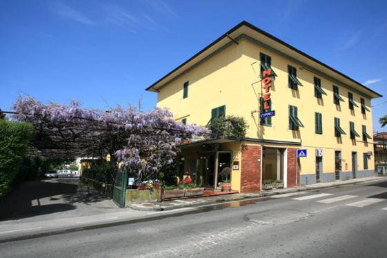 un bâtiment sur le côté d'une rue avec un arbre à fleurs dans l'établissement Hotel Stipino, à Lucques