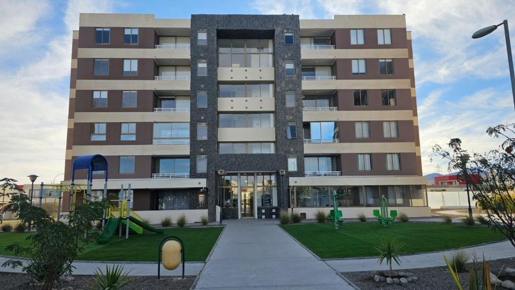 ein großes Gebäude mit einem Spielplatz davor in der Unterkunft comodidad-seguridad-conectividad in Calama