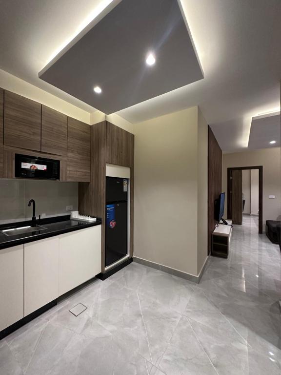 a kitchen with white cabinets and a black refrigerator at Chic Apartments For Rent ave2-4 in Amman