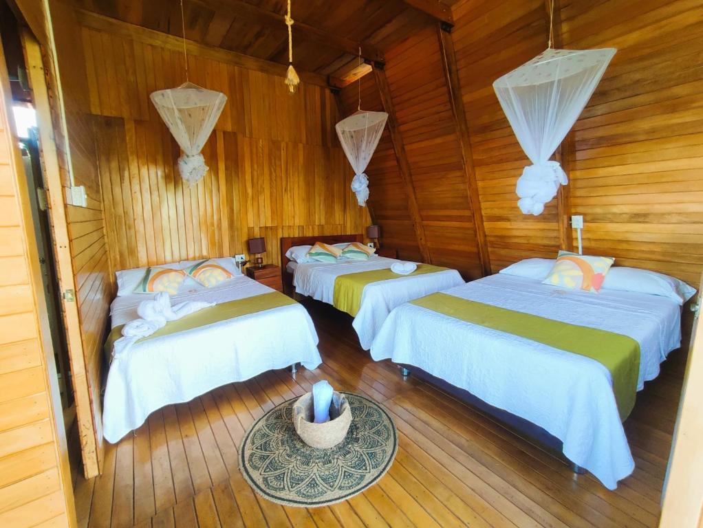 three beds in a room with wooden walls at Casa Alpina - Barlovento Ecolodge Tarapoto - Familiar in Tarapoto