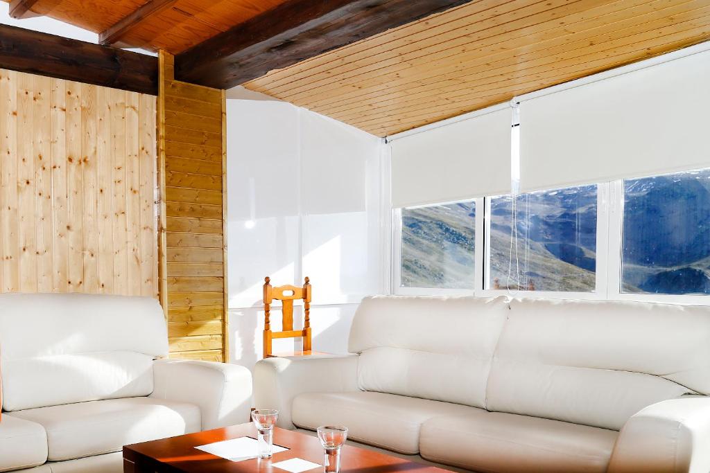 una sala de estar con muebles blancos y ventanas grandes. en Apartamentos Kilimanjaro Pepe Marin en Sierra Nevada