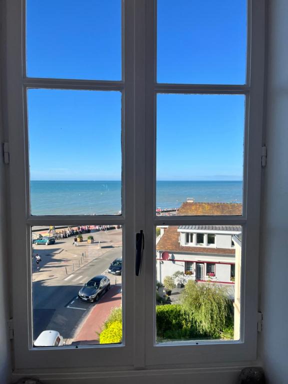 Una ventana con vista a una calle y al océano. en Belle vue sur la mer, en Veules-les-Roses
