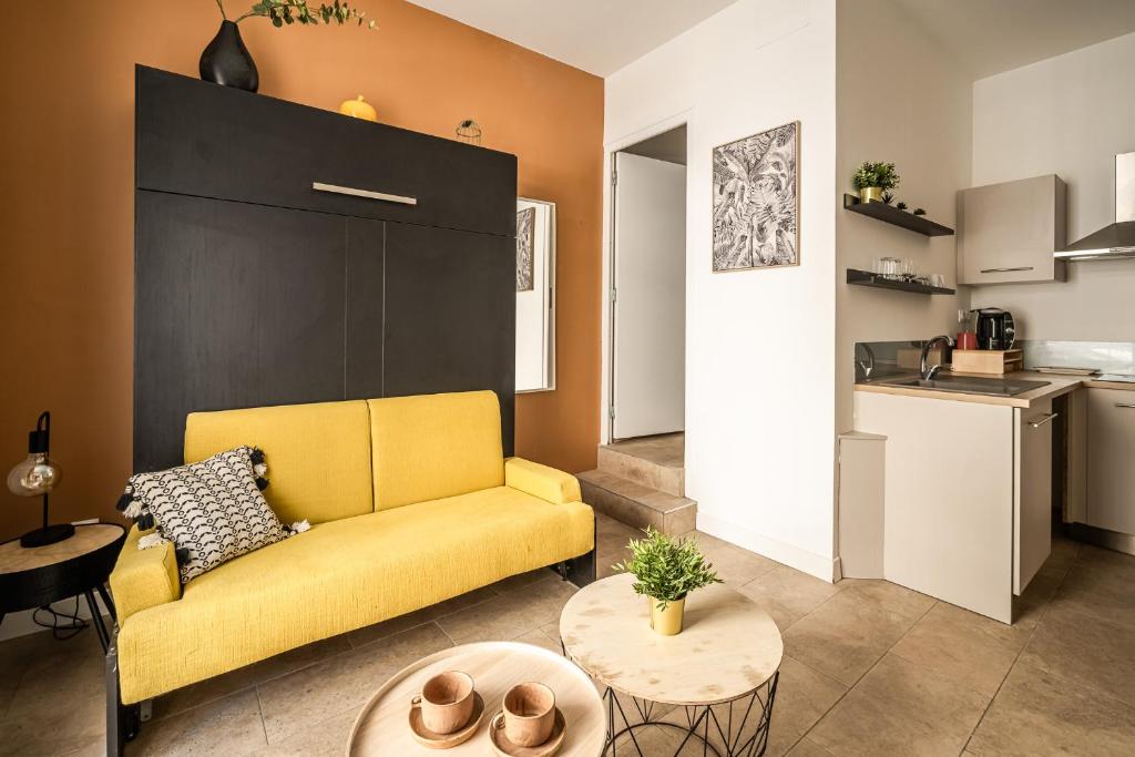 un salon avec un canapé jaune et une table dans l'établissement Studio Hélios Narbona, à Narbonne