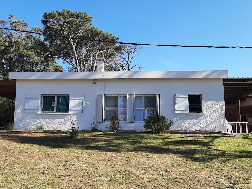 une maison blanche avec deux fenêtres dans une cour dans l'établissement Chalet Labuada a 3 cuadras del mar, à La Aguada