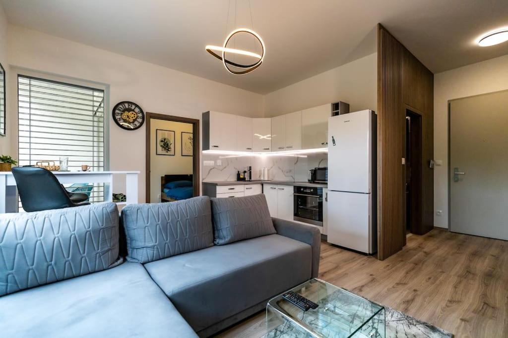 a living room with a blue couch and a kitchen at Aurora, Banská Bystrica in Banská Bystrica
