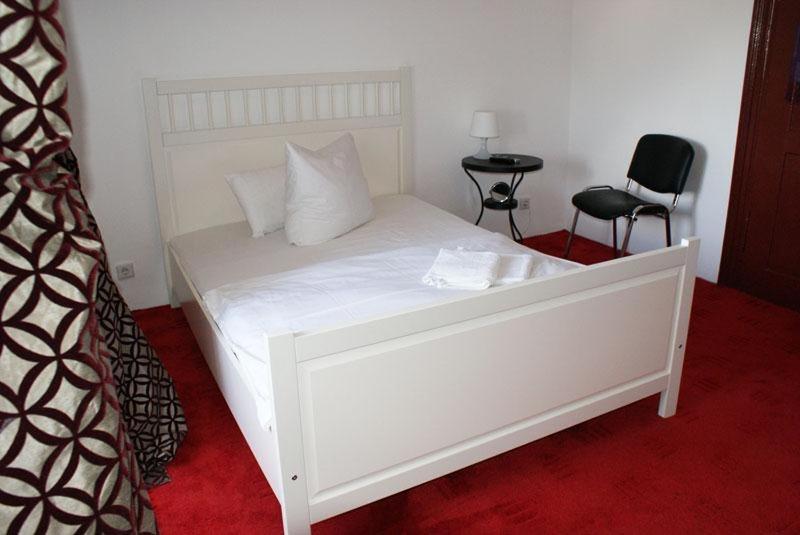 a white bed in a room with a red carpet at Pension De Lux Königsbrunn in Königsbrunn