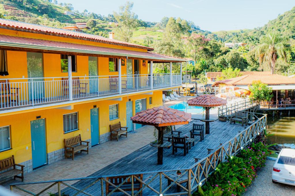 a hotel balcony with tables and chairs and a pool at Pousada Brilho do Sol in Serra Negra