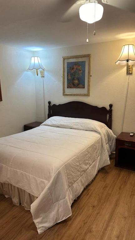 a bedroom with a large white bed with two lights at Gaard motel in Foxborough