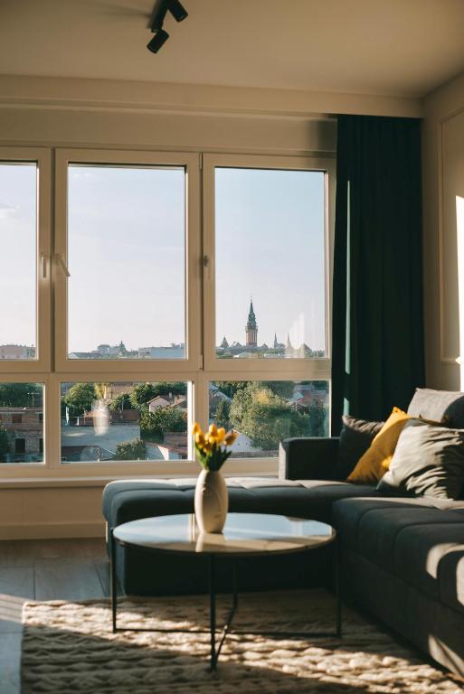 a living room with a couch and a table and windows at Tara View Apartment in Subotica