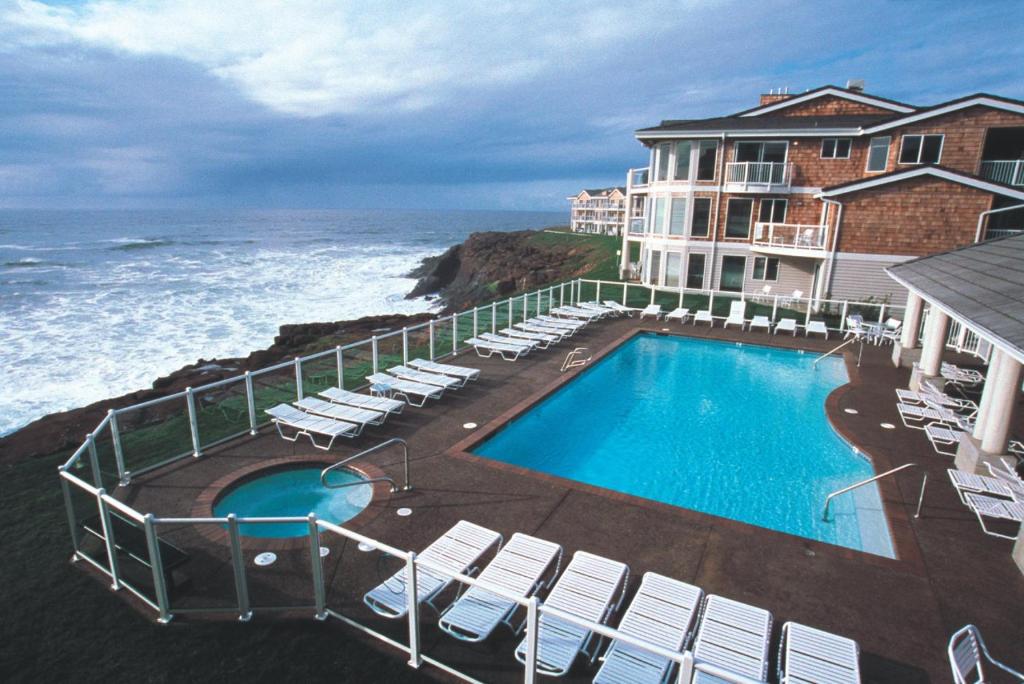 a resort with a swimming pool and chairs and the ocean at Worldmark Depoe Bay 2BD - Sleeps 6 in Depoe Bay