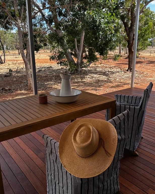 a hat sitting on a wooden table on a deck at Curlew Cottage Katherine in Katherine