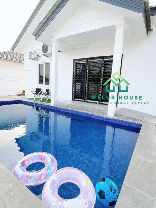 a swimming pool with two inflatables in front of a house at Melur House - Private Pool, Jacuzzi, Bbq, Netflix, PS4 in Malacca
