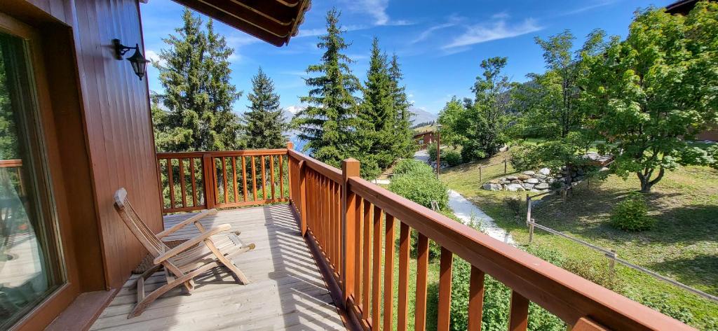 Elle comprend un balcon doté d'une balustrade en bois et d'une chaise en bois. dans l'établissement Duplex Luxueux 200m2 Niché sur les Pistes - Paradis Lodge pour 14 Personnes, à Bourg-Saint-Maurice