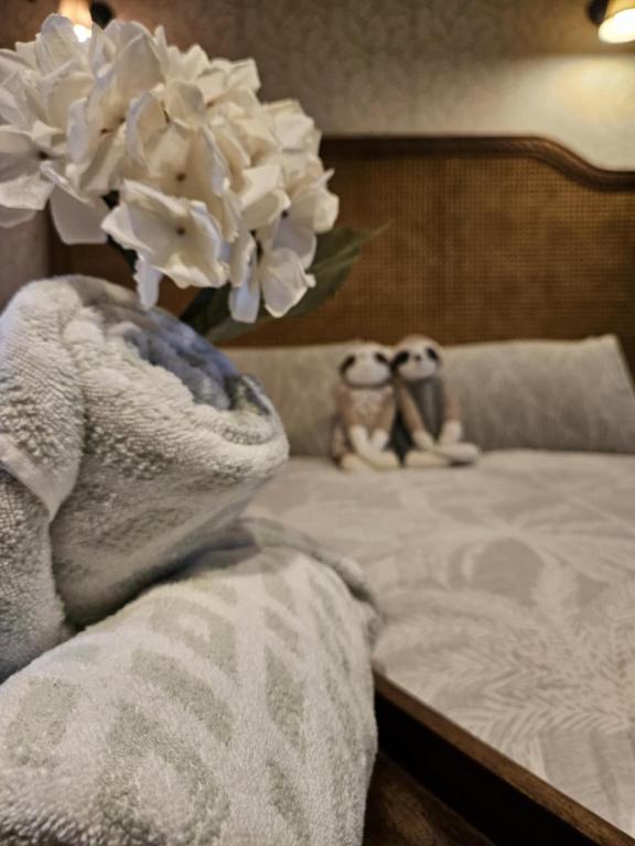 two stuffed animals sitting on a bed with a vase of flowers at The Gamekeepers Spa Cottage in Tamborine Mountain in Mount Tamborine