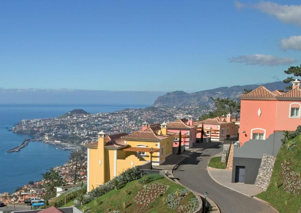 Eine Stadt auf einem Hügel mit dem Ozean im Hintergrund in der Unterkunft Balancal Apartments and Villas Palheiro Village in Funchal