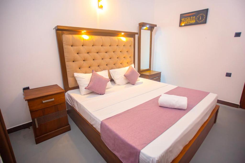 a bedroom with a large bed with a wooden headboard at 2BR Family Getaway Hikkaduwa- Sleep 6 - Surfing- Bikes and airport drop-off in Hikkaduwa