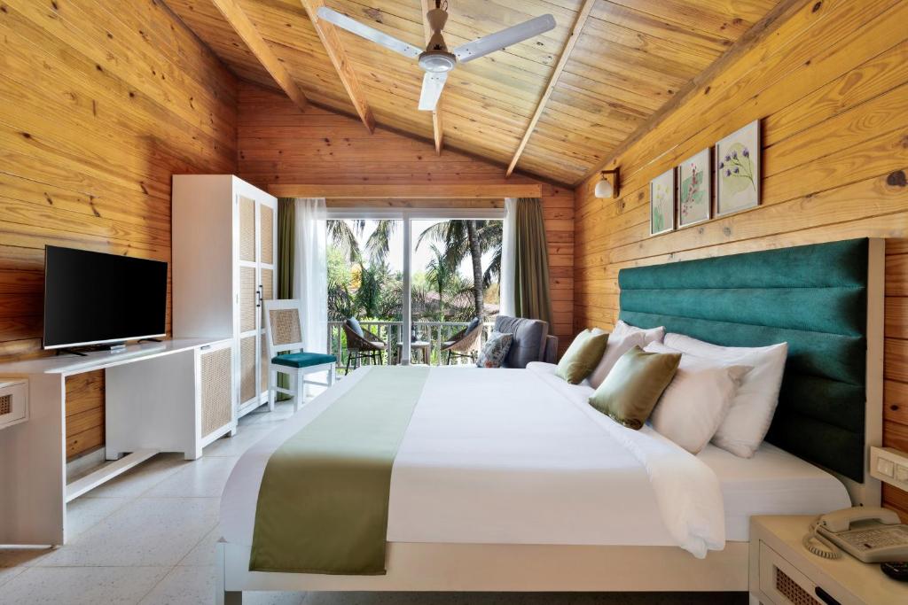 a bedroom with a large bed and a television at Aralea Beach Resort By Stone Wood Premier in Morjim