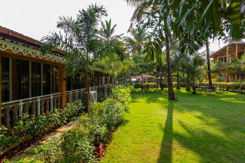a yard with palm trees and a building at Aralea Beach Resort By Stone Wood Premier in Morjim