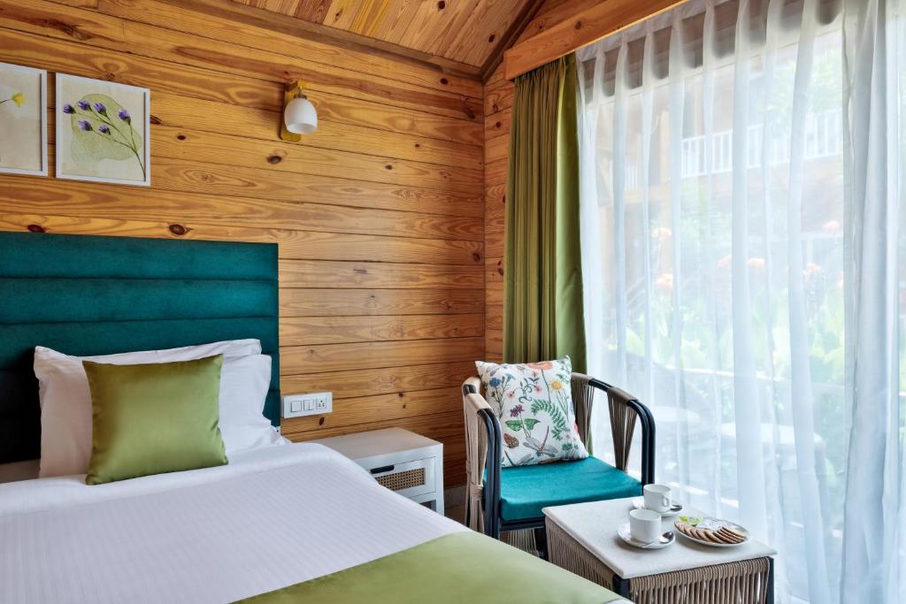 a bedroom with a bed and a chair and a window at Aralea Beach Resort By Stone Wood Premier in Morjim