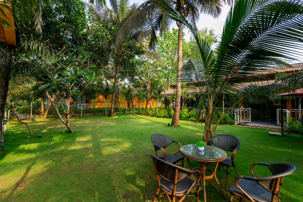 a table and chairs in a yard with palm trees at Aralea Beach Resort By Stone Wood Premier in Morjim