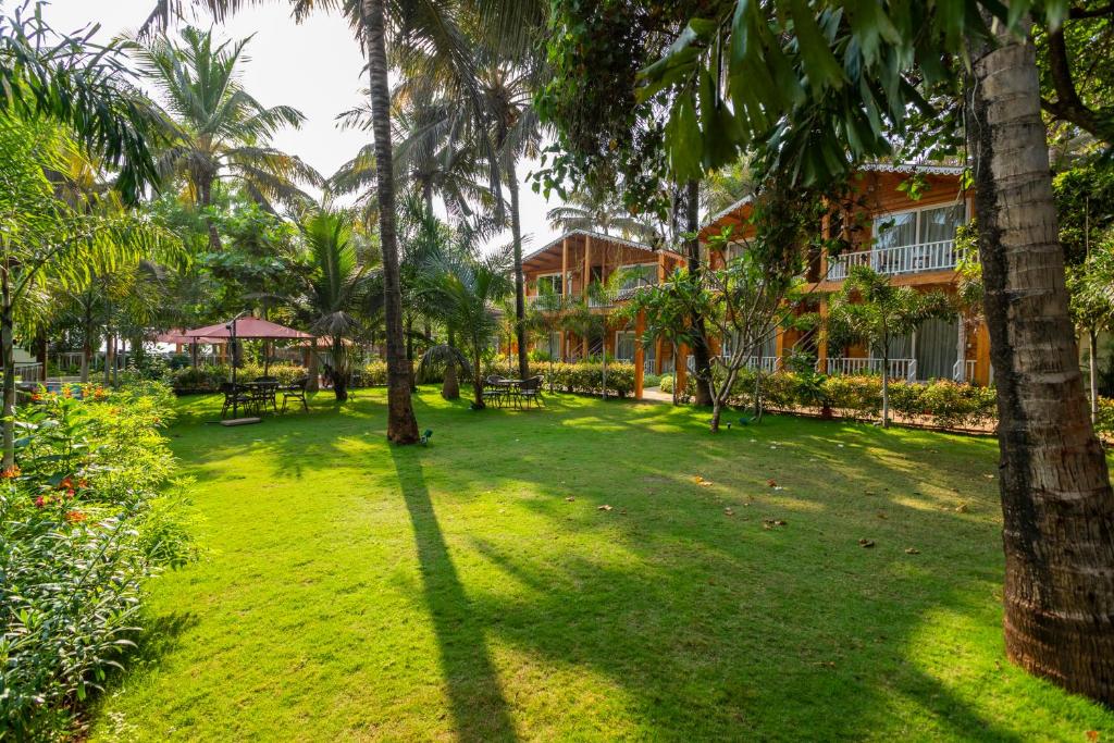 a lawn in front of a resort with palm trees at Aralea Beach Resort By Stone Wood Premier in Morjim