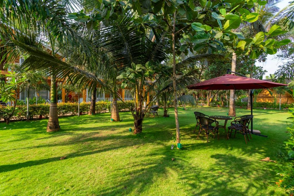 a table and chairs under an umbrella under palm trees at Aralea Beach Resort By Stone Wood Premier in Morjim
