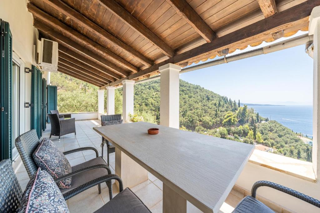 a table and chairs on a balcony with a view of the ocean at Villa Salvia in Katávolos