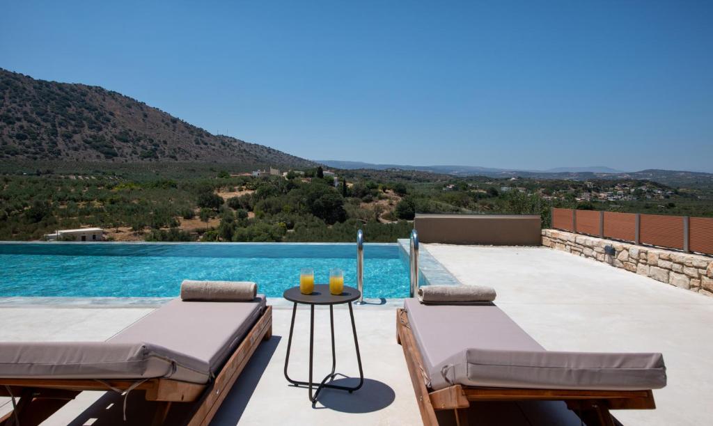 a pool with two beds and a table with a view at Calmo Luxury Villas, with Pool Tranquil Elegance, By ThinkVilla in Lamerianá