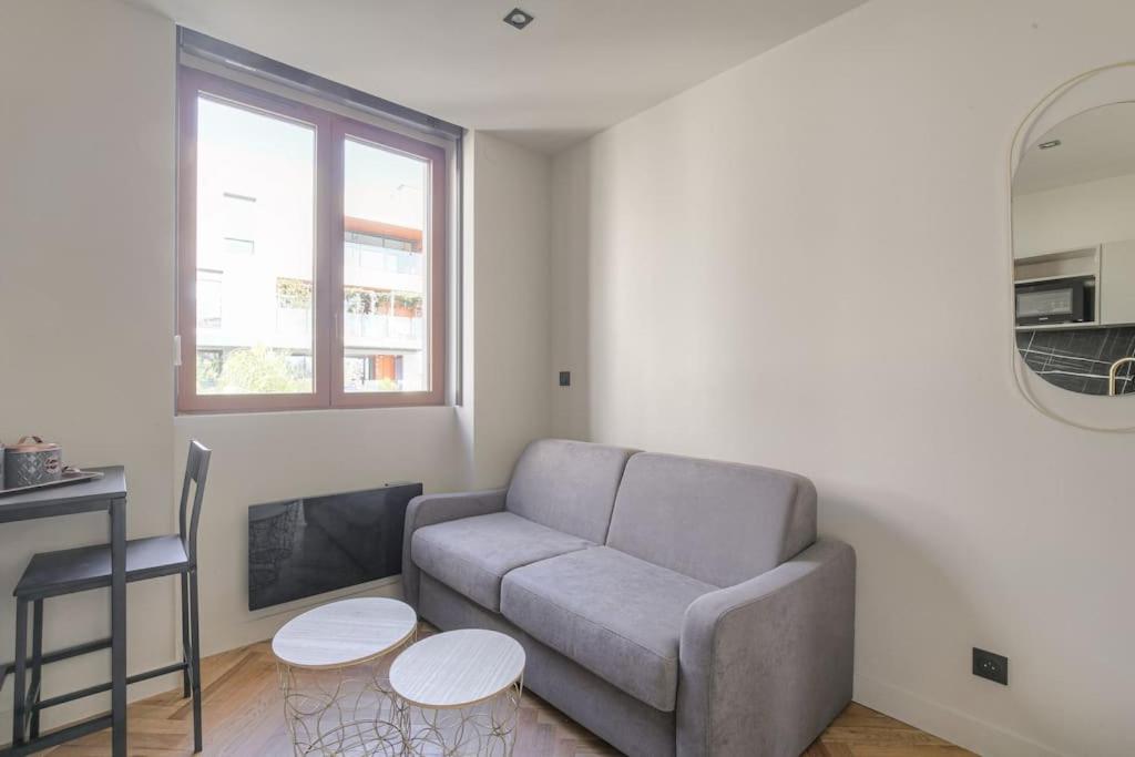 un salon avec un canapé et deux tables dans l'établissement Studio confortable près de la Croix-Rousse, à Caluire-et-Cuire