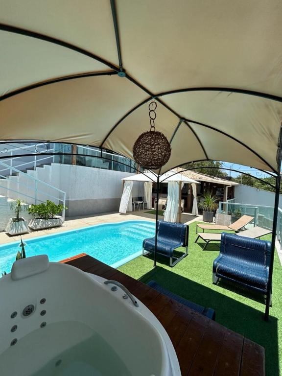 a bath tub in a tent next to a swimming pool at Casa com piscina área gourmet Enseada Azul in Guarapari