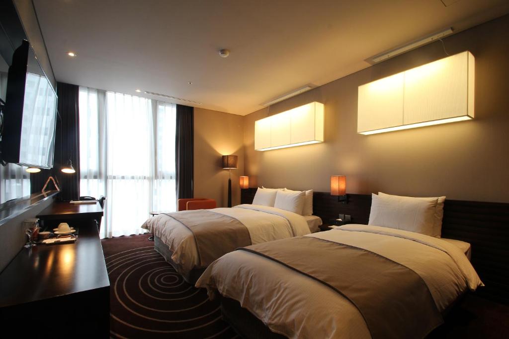 釜山的住宿－路易斯漢密爾頓百斯特酒店海雲臺，两张床铺,位于酒店客房,墙上有灯