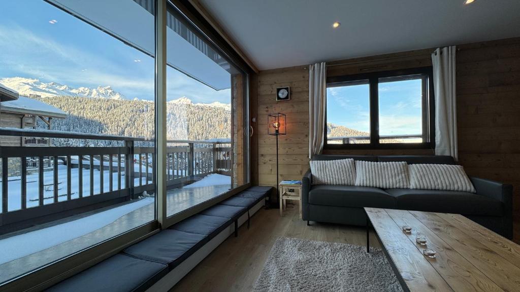 un salon avec un canapé et une grande fenêtre dans l'établissement Appartement Résidence Ourse Bleue, à Courchevel