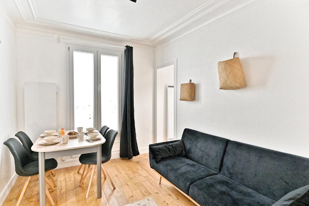 un salon avec un canapé noir et une table dans l'établissement Séjour dans le Quartier Batignole Paris 17ème, à Paris