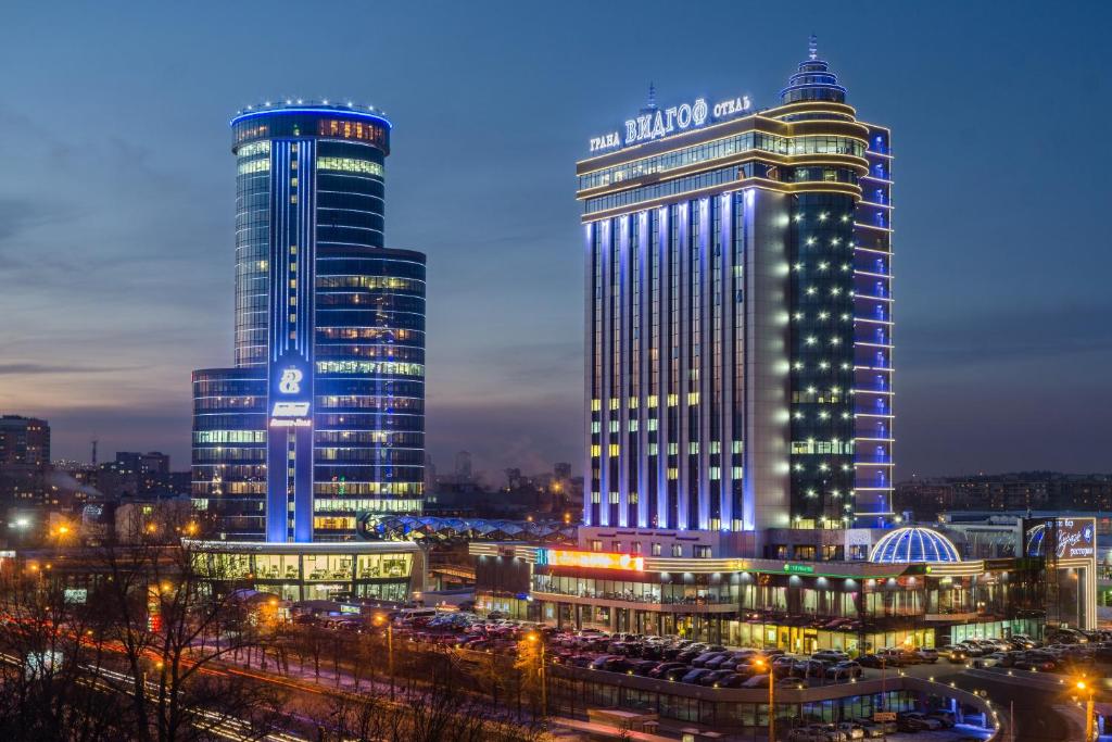 dos edificios altos en una ciudad por la noche en Grand Hotel Vidgof, en Chelyabinsk