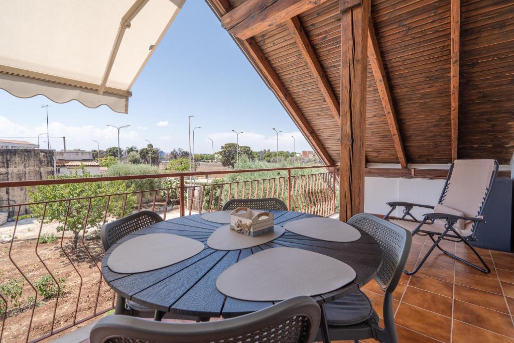 Un patio con una mesa y sillas en un balcón. en Ferienwohnung Villa Segesta, en Siracusa