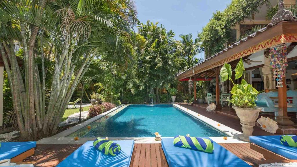 a swimming pool with chairs and a house at Villa Kaja by Nagisa Bali in Seminyak