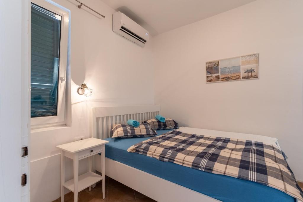 mała sypialnia z łóżkiem i oknem w obiekcie Apartman GREEN & BLUE w Novalji