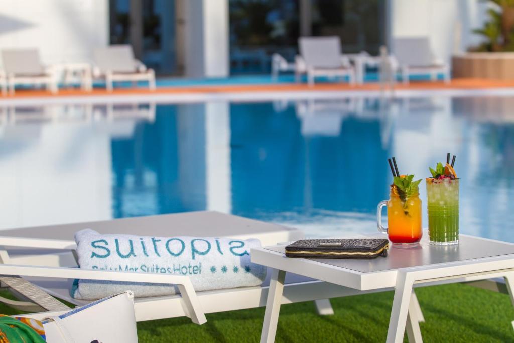 a table with two drinks on it next to a pool at ESTIMAR Calpe Suitopia in Calpe