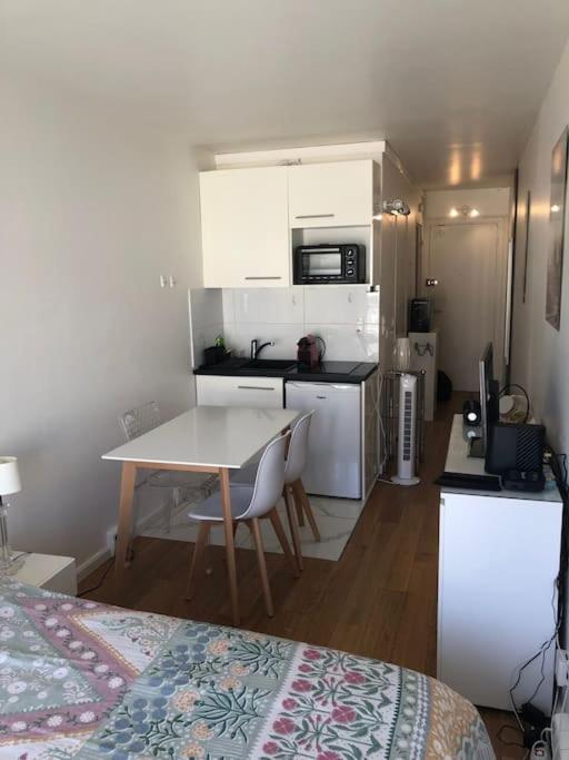 Cette chambre comprend une cuisine, une table et un lit. dans l'établissement Nice flat St Germain en Laye centre 30 minutes to Paris, à Saint-Germain-en-Laye