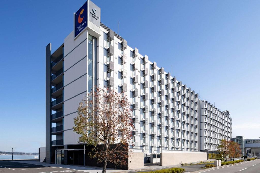 a large white building with a clock on top of it at Comfort Hotel Central International Airport in Tokoname