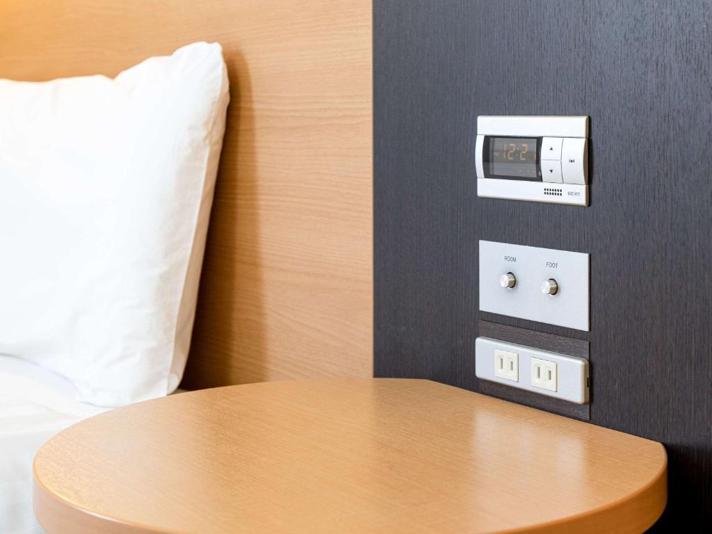 a table in a hotel room with a clock on the wall at Comfort Hotel Central International Airport in Tokoname