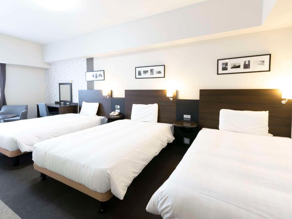 a hotel room with two beds with white sheets at Comfort Hotel Central International Airport in Tokoname