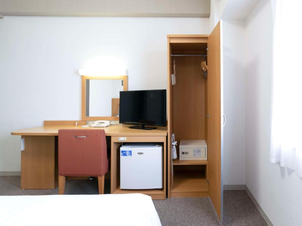 a room with a desk with a computer and a television at Comfort Hotel Central International Airport in Tokoname